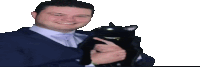 a man in a suit and tie is holding a black cat