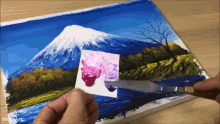 a painting of a mountain and a river is being painted