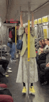 a woman is hanging upside down on a subway car
