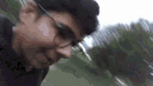 a man wearing glasses is standing in a field and making a funny face .