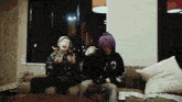 two young men sitting on a couch with money on it