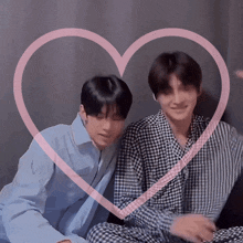 two young men are sitting next to each other with a pink heart in the background