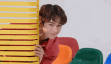 a young man peeking out from behind a yellow railing