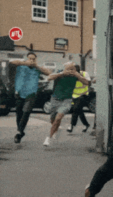 a group of men are running down a street while a stop sign is in the background .