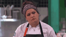 a woman in a chef 's uniform is wearing a headband