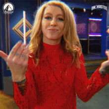 a woman in a red dress is holding a lollipop in her hand and says ink master