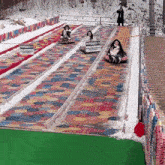 a group of people are riding down a snow slide with a sign that says ' a warning ' on it