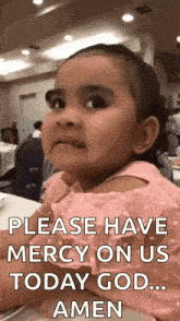 a little girl is sitting at a table and making a funny face while asking for mercy on us today god .