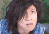 a close up of a person 's face with messy hair and a denim vest