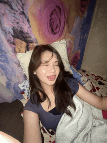 a girl laying in bed with her eyes closed and her tongue out