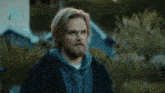 a man with long blonde hair and a beard wearing a blue hoodie