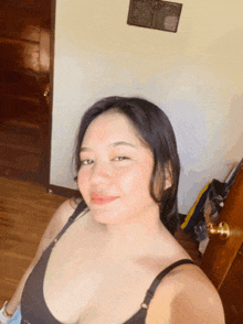 a woman in a black bra is taking a selfie in front of a door