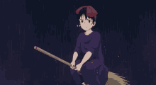 a young girl is sitting on a broom in the rain .
