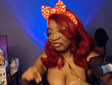 a woman with red hair and glasses is wearing a red and white polka dot headband