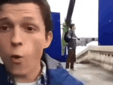a man in a blue jacket is standing in front of a blue wall .