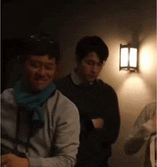 a man with a scarf around his neck is standing next to another man