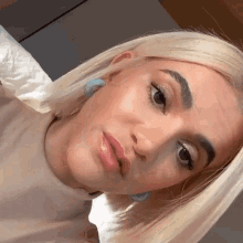 a close up of a blonde woman 's face with blue earrings