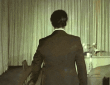 a man in a suit is standing in front of a curtain