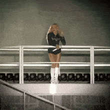 a woman stands on a balcony holding a microphone and wearing shorts that say ' aa ' on them