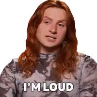 a woman with long red hair is wearing a tie dye shirt and says i 'm loud