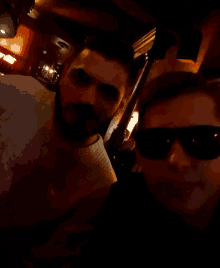 two men wearing sunglasses are posing for a picture in a dark room