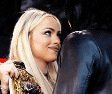 two women are standing next to each other and one is holding a wrestling championship belt .