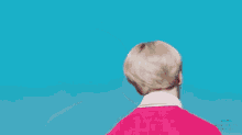 a person with blonde hair is wearing a red shirt and looking up