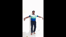 a man in a blue shirt and black pants is standing on one leg with a tennis ball in his hand .
