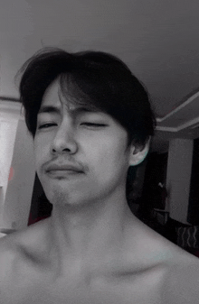 a man without a shirt is making a funny face with his eyes closed .