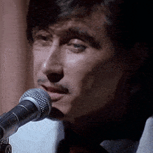 a close up of a man singing into a microphone with the letter n visible