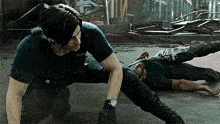 a man is kneeling down next to another man who is laying on the floor .
