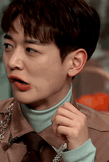 a young man wearing a turtleneck and tie is making a funny face