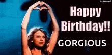 a woman is making a heart shape with her hands in front of a sign that says `` happy birthday ! gorgeous '' .