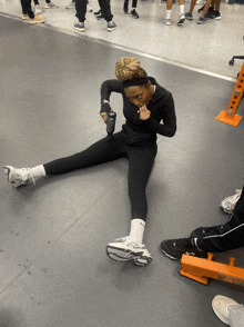 a woman sits on the floor stretching her legs while holding a bottle