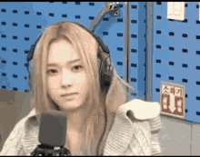 a woman wearing headphones stands in front of a microphone in a room