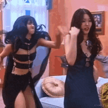 two women are standing next to each other in a living room and dancing .