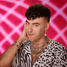 a man wearing a zebra print shirt and earrings is making a funny face