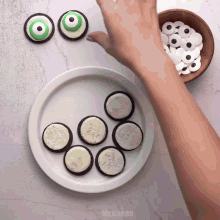 a person is decorating oreos with green frosting and black eyes