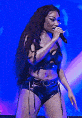 a woman with long hair singing into a microphone on stage