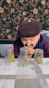 a man in a purple hat is playing with three glasses