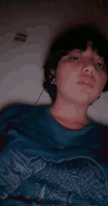 a young boy wearing headphones and a blue shirt is sleeping on a bed .