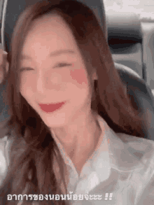 a woman is smiling while sitting in a car with her eyes closed .