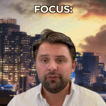 a man with a beard stands in front of a city skyline and the word focus is above him