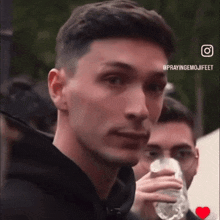 a man drinking water from a bottle with the hashtag prayingemojifeet on the bottom