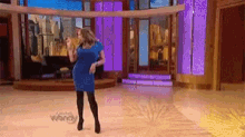 a woman in a blue dress is dancing on a stage with the word wendy in the background
