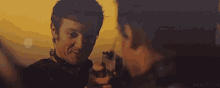 a man is pointing a gun at another man while smiling .