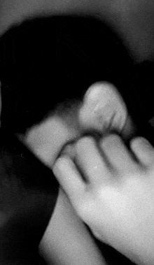 a close up of a person covering their face with their hands