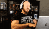 a man wearing headphones and a shirt that says what does n't kill you is typing on a laptop
