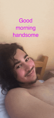 a man with a beard is laying in bed with the words good morning handsome written above him