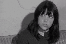 a young girl is sitting on a wicker couch and looking up .